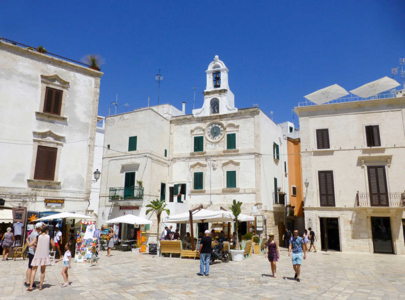 people walking around a square with a tower clock