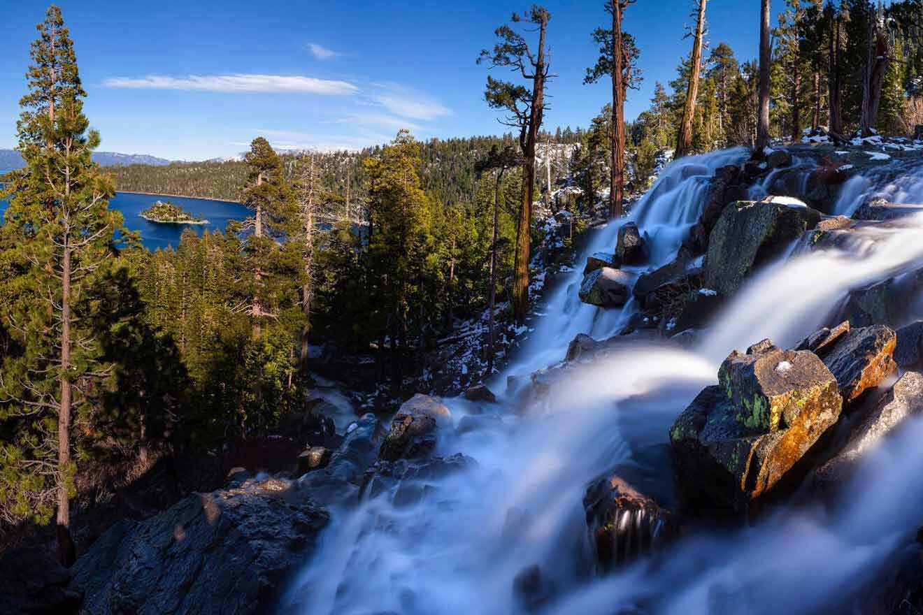 waterfall near a lake surrounded by trees