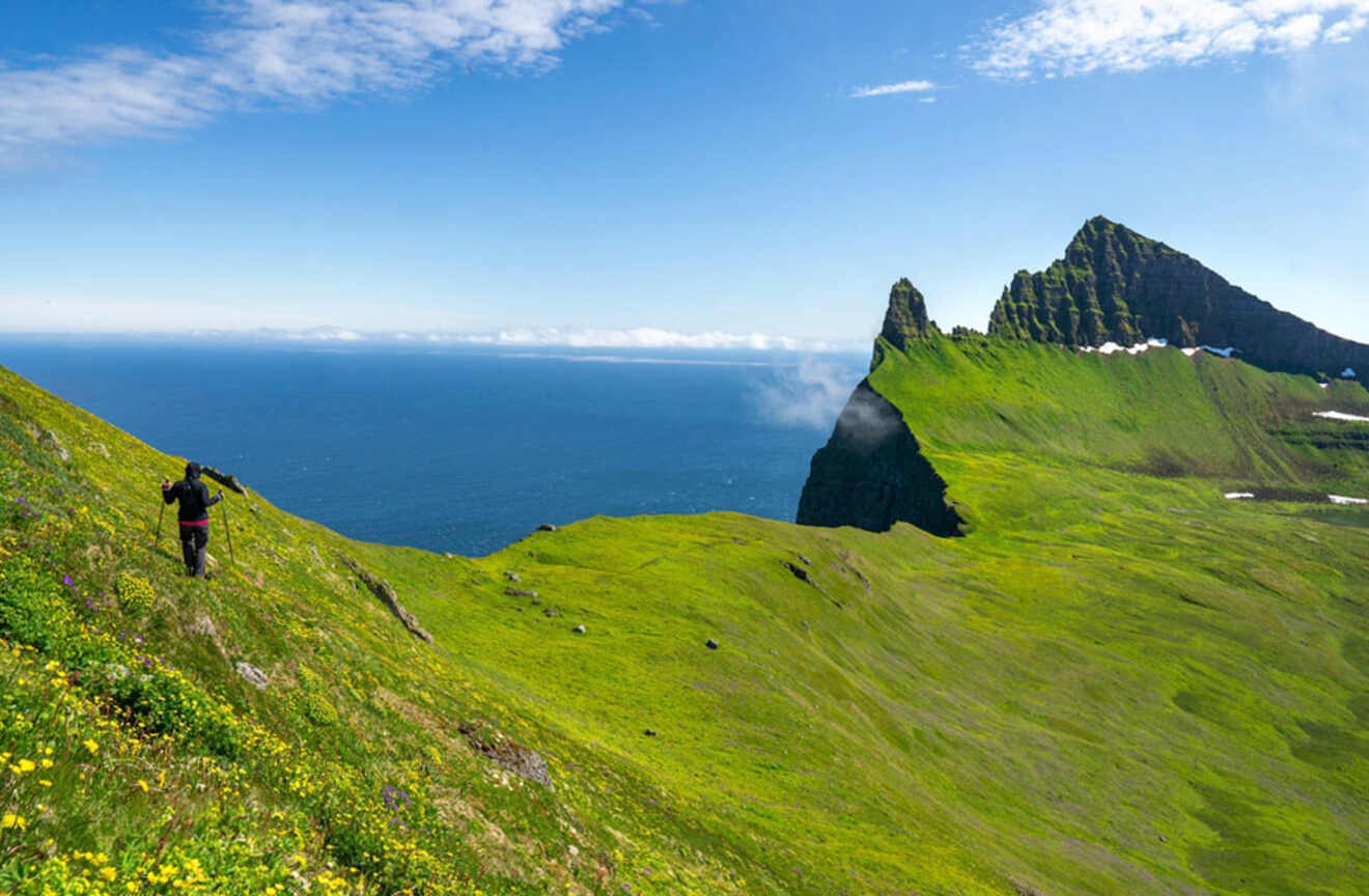 a person hiking on a cliff mountain next to the ocean