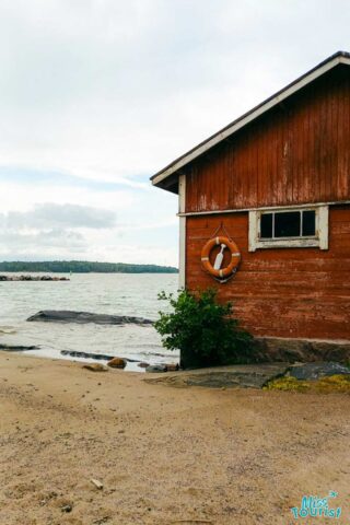 A red building on the shore of a body of water.