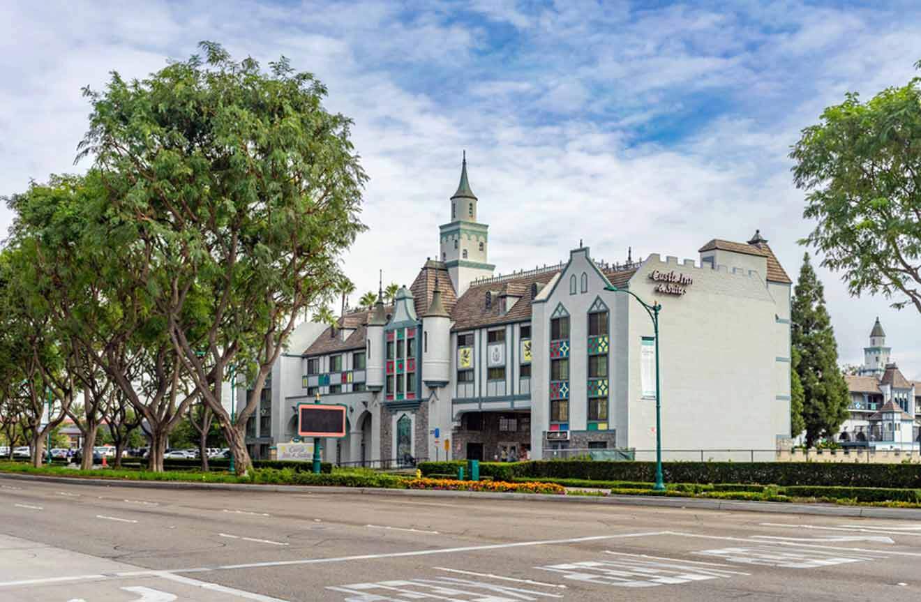 A white building with a tower on the street with trees is front of it