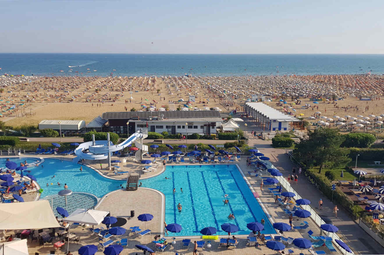 An aerial view of a beach with a swimming pool and umbrellas.