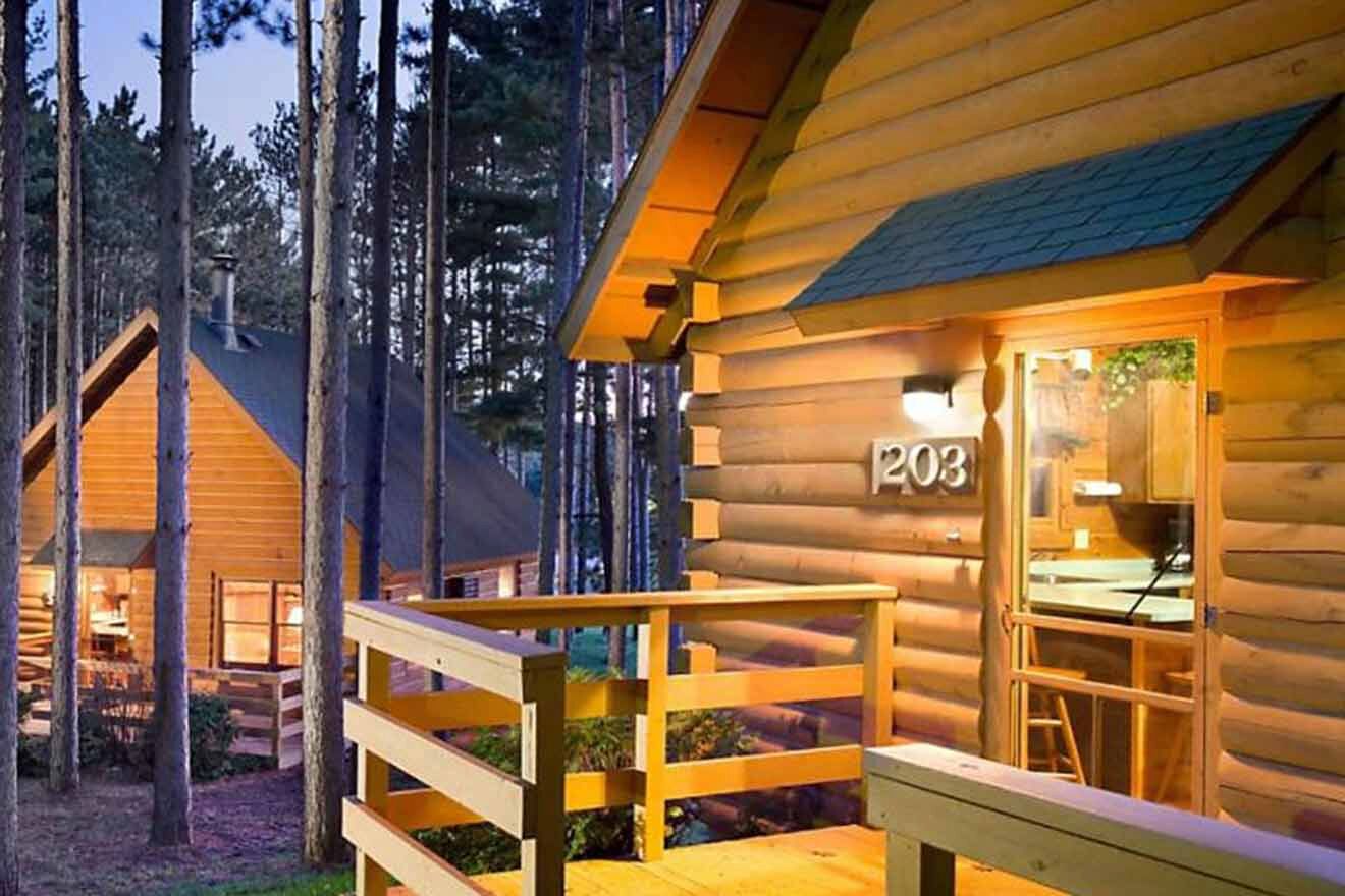 Two log cabins in the woods at dusk.