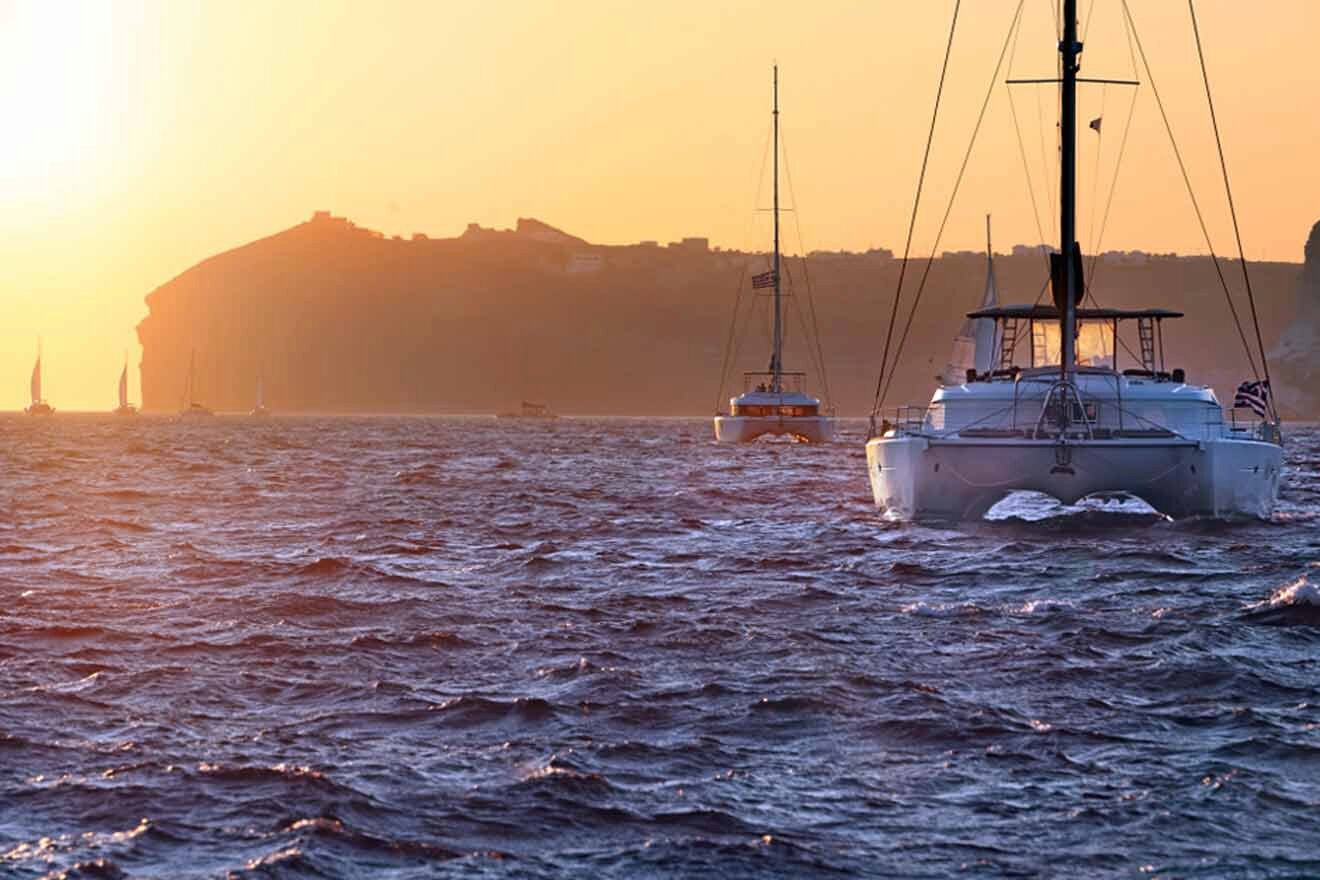 cataraman boats with a hill in the background at sunset