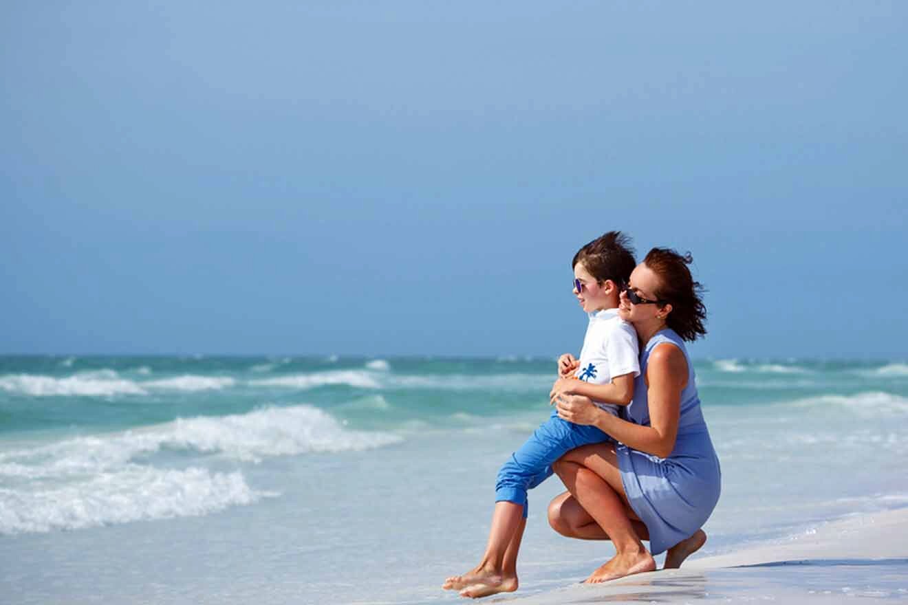 A woman holding a child on the beach.