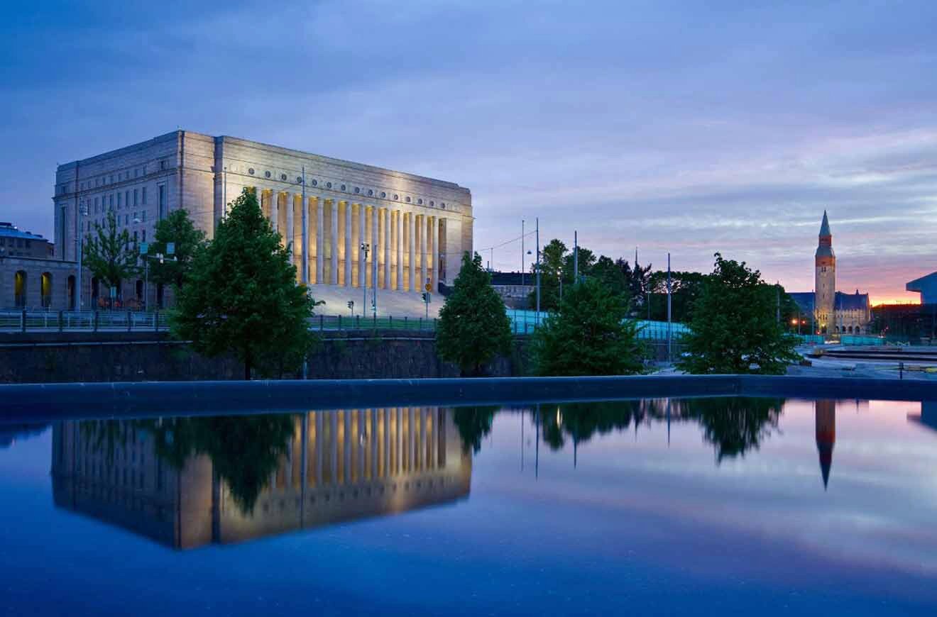 A building is reflected in a body of water at dusk.