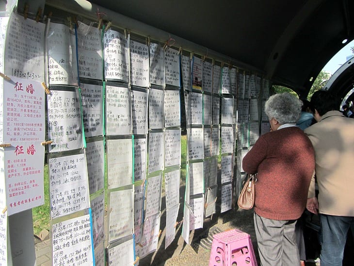 peopl reading signs at the marriage market wall