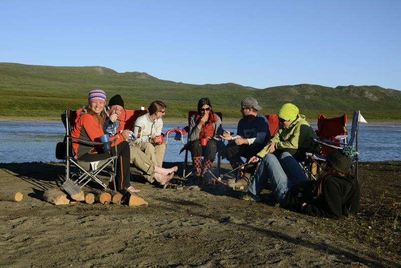 people sitting by a lake in camp chairst alking