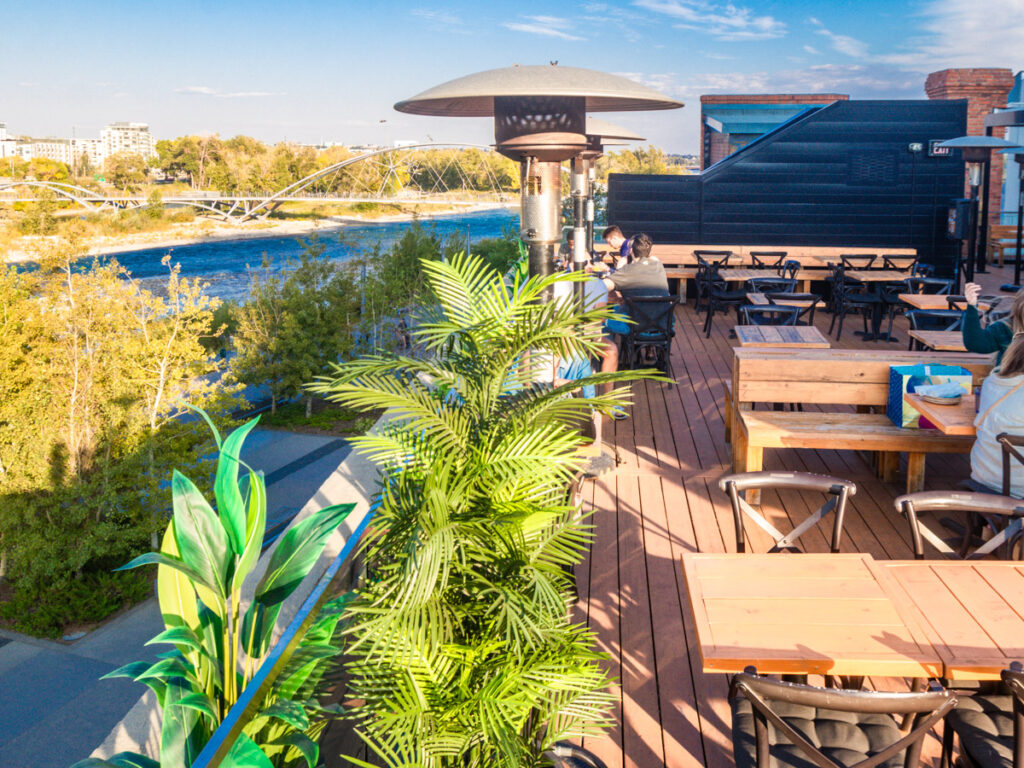 tables and chairs on rooftop patio with bow river views