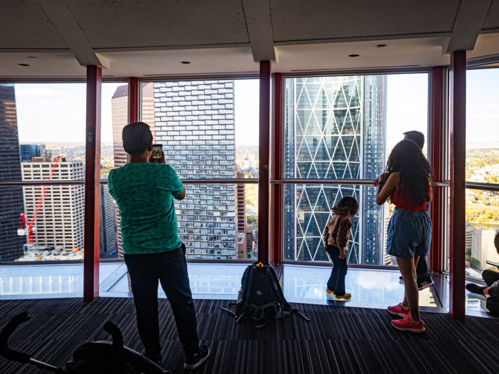 people looking out glass window at buildings