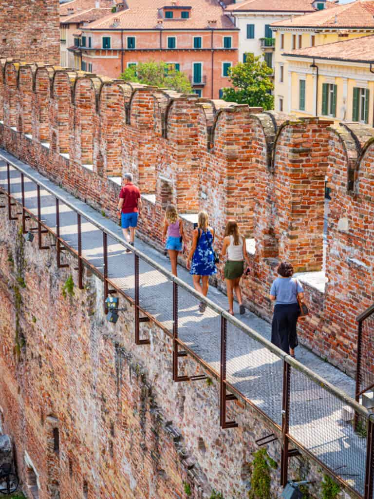 caz and girls walking along elevated brick walkway in castle