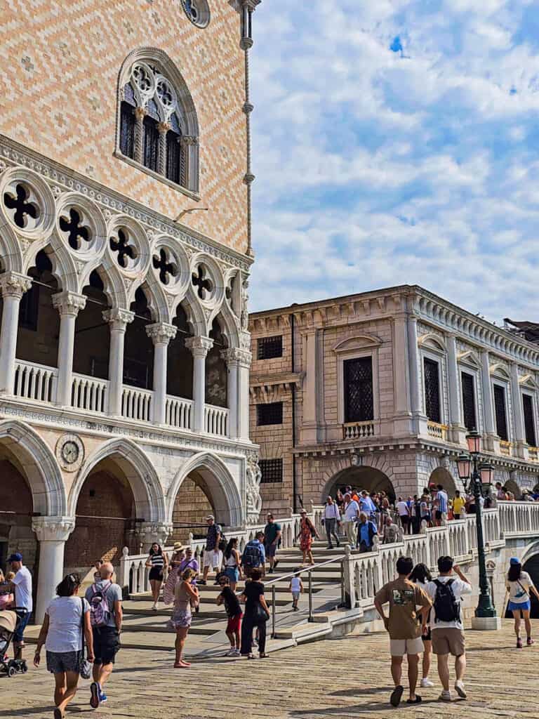 people walking over bridge next to doge palace