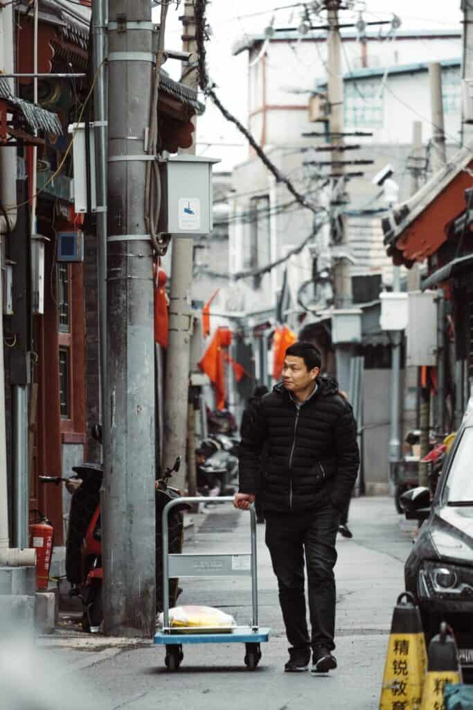 man walking down alley pulling cart