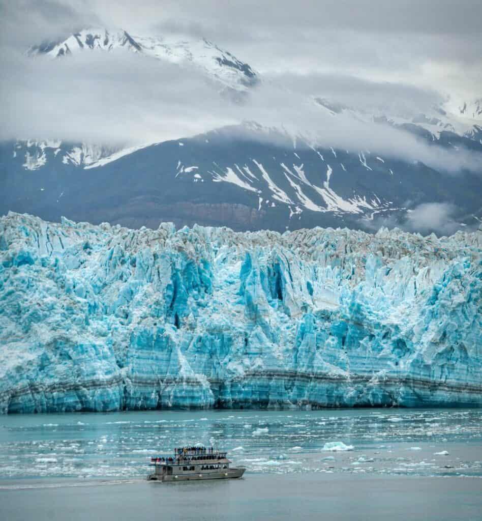 boat dwarfed by glacier in front of mountain