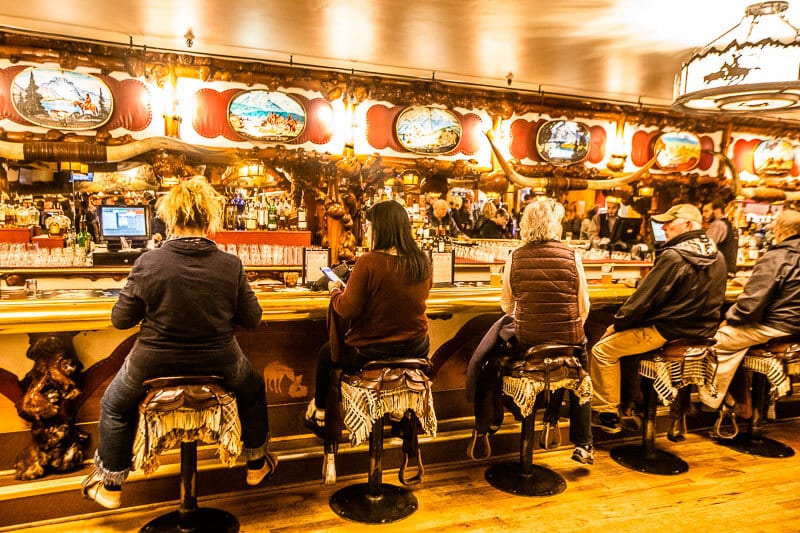 people sitting on Saddles for seat at Million Dollar Cowboy Bar in Jackson 