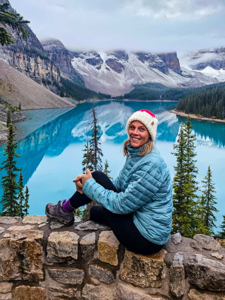 caz sitting on rock wall smiling in front of moraine lake canada