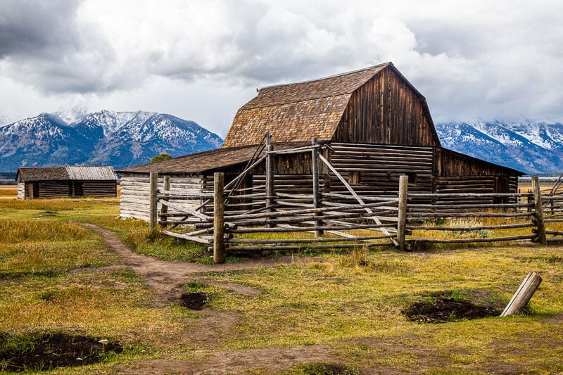 old wooden home with log fence on Mormon Row with teton mountains behind it. 