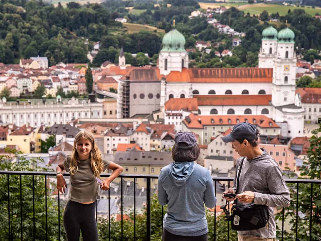 Young girl with two adults standing at a fence overlooking a city view