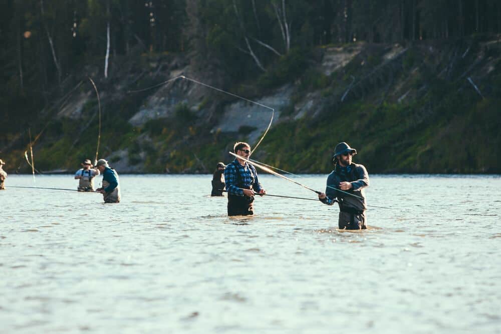 people standing in river fly fishing