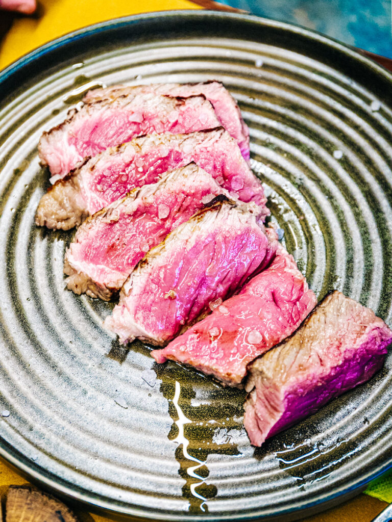 plate with slices of rare cooked meat