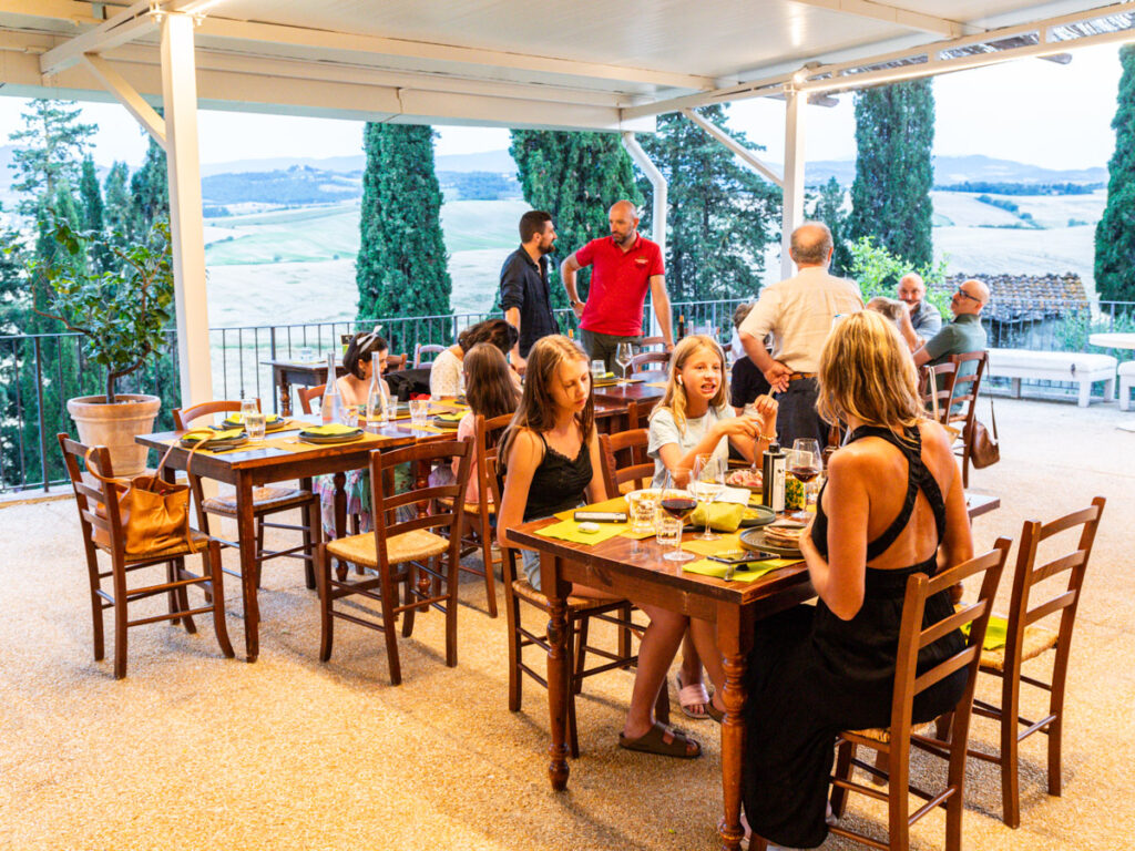 caz and girls sitting at restaurant table with views of tuscan countryside