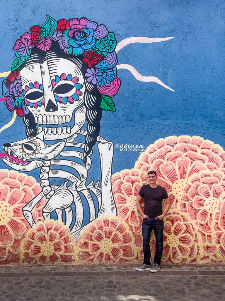 Matt Kepnes standing next to a mural in Oaxaca, Mexico