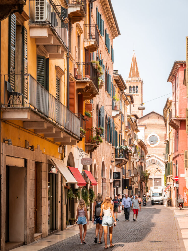 caz and girls walking down street in verona with colorful buildings on either side