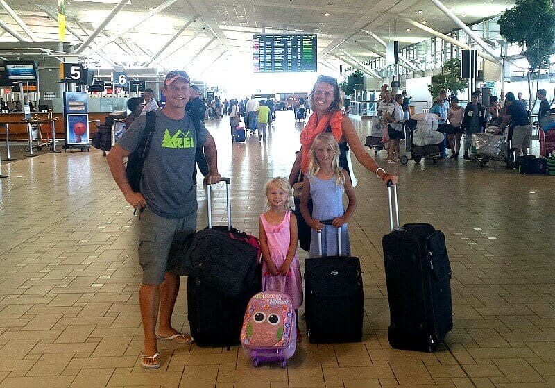 family at airport with bags posing for camera