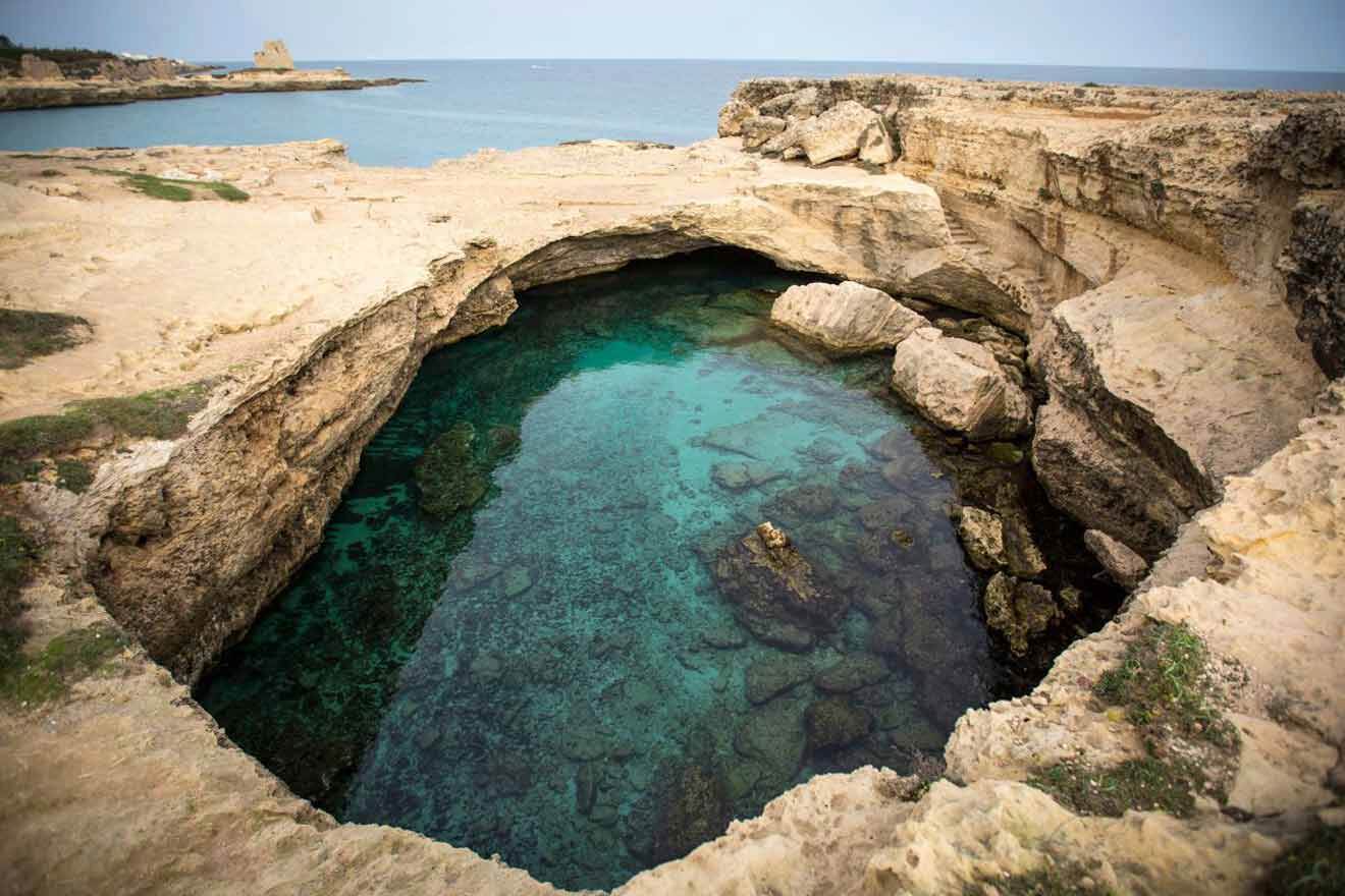 A cave with clear water in the middle of a cliff.