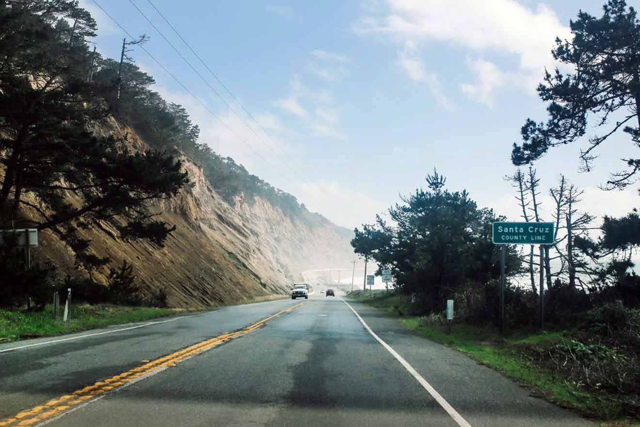 A road with cars driving down the side of a cliff.