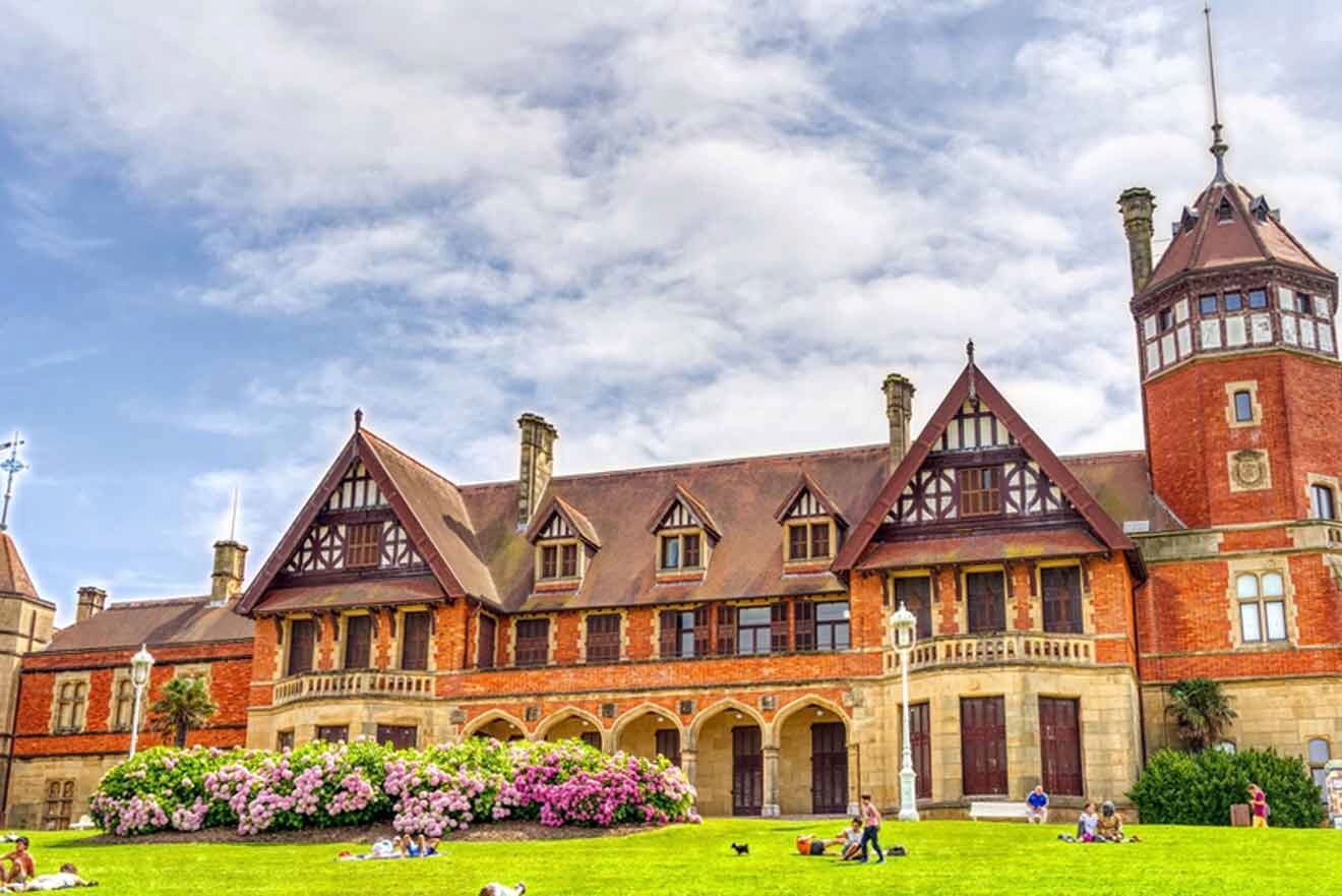 People are sitting on the grass in front of a large building.