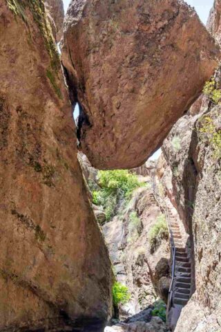 A person is climbing up a large rock in a canyon.