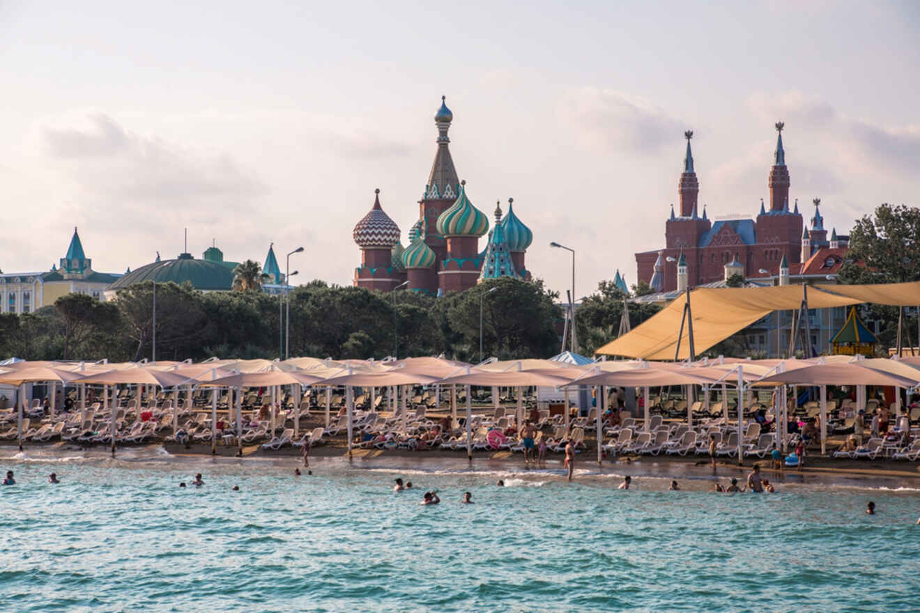 A beach with umbrellas and a castle in the background.