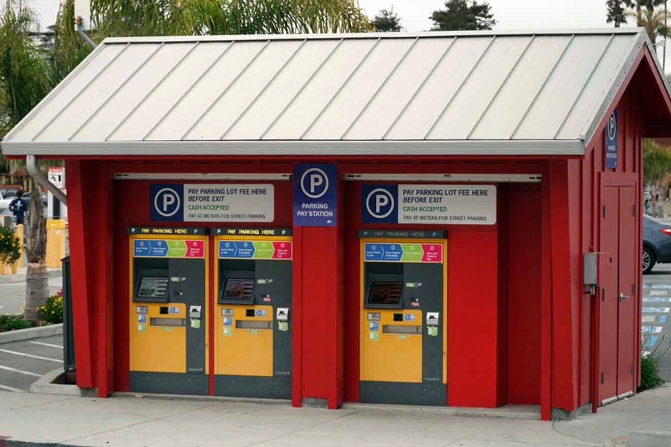 A red and yellow vending machine at a parking lot.