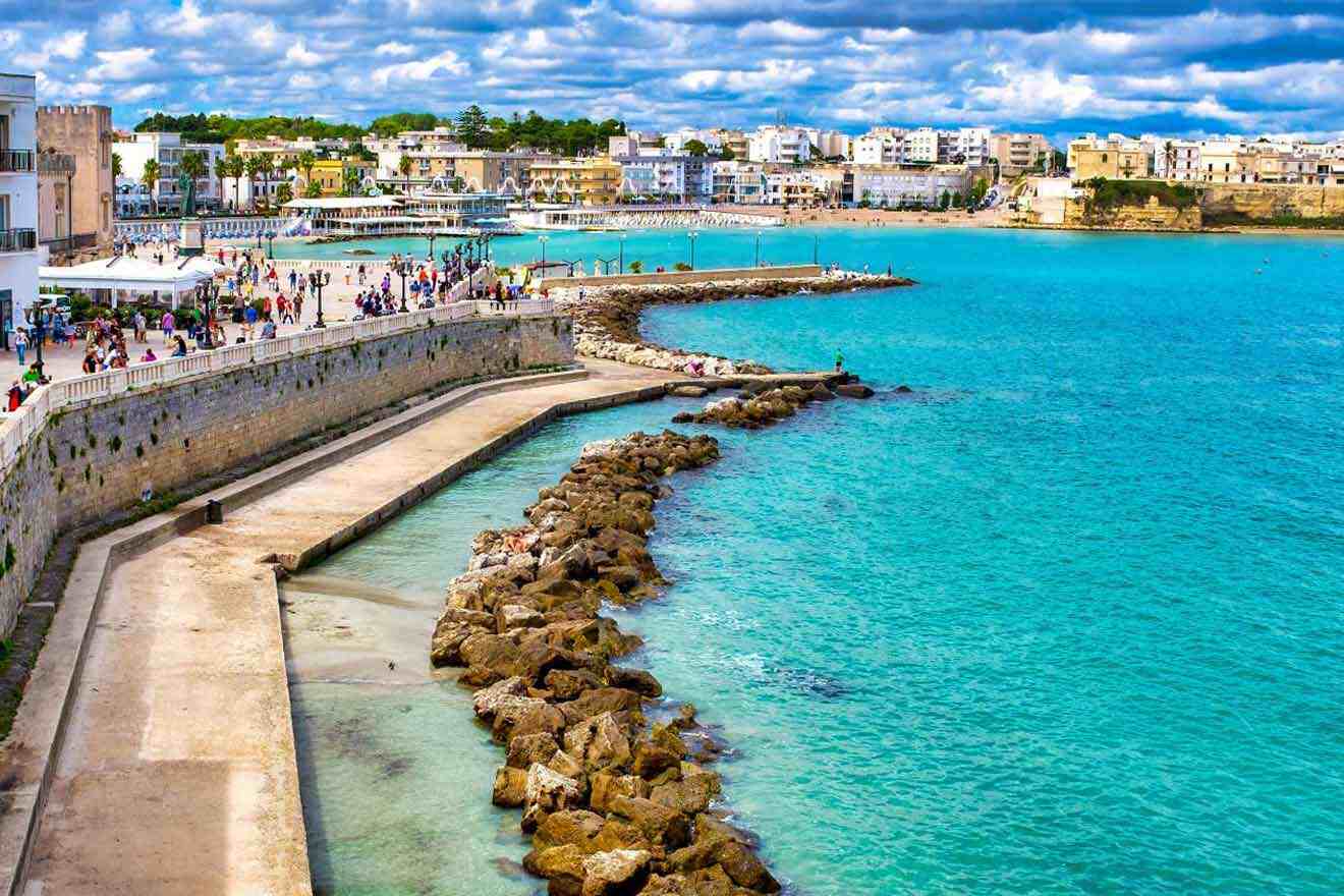 A city on the coast with people walking along the shore.