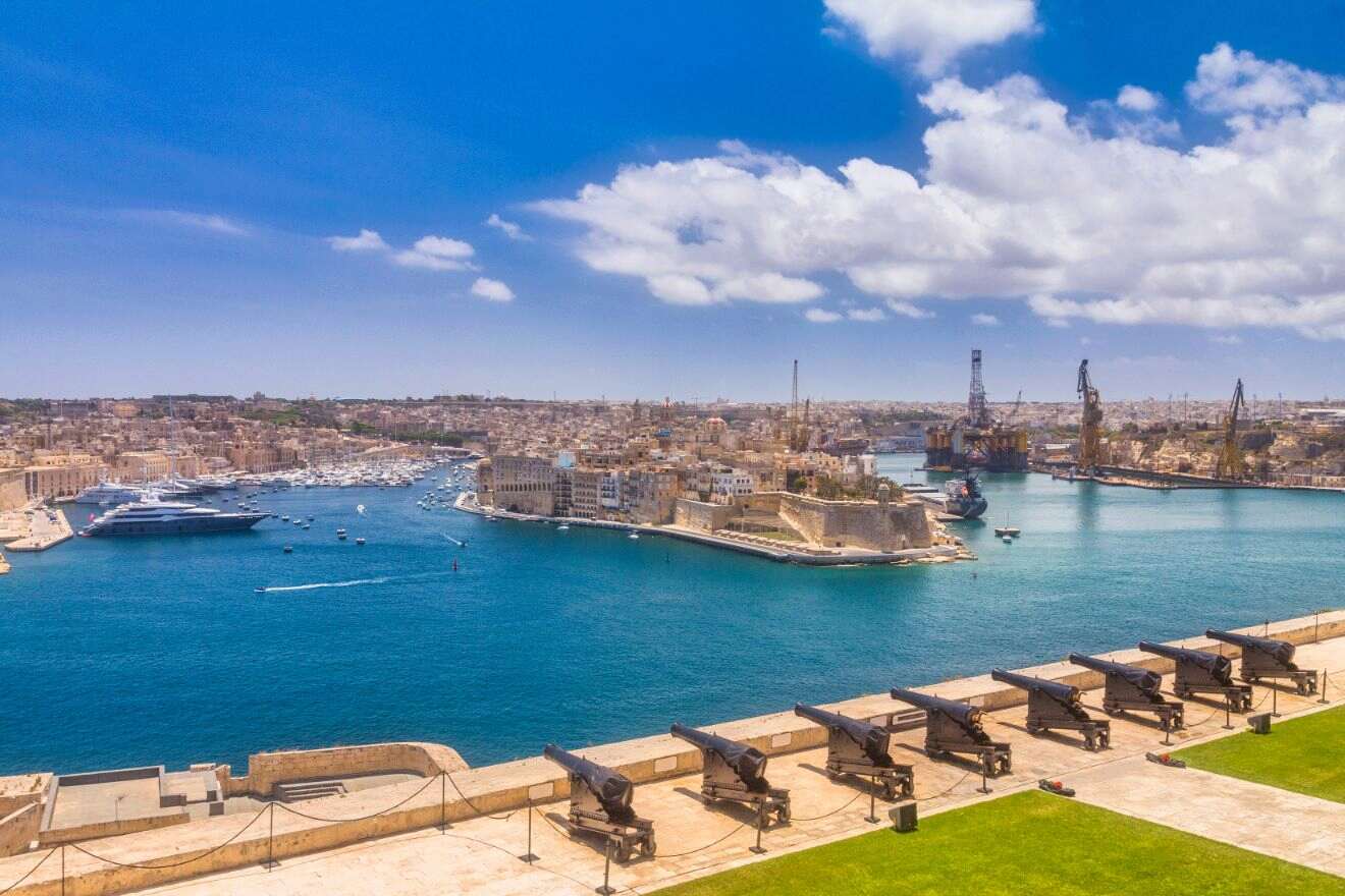 A view of the city with boats and cannons sitting on top of a fort