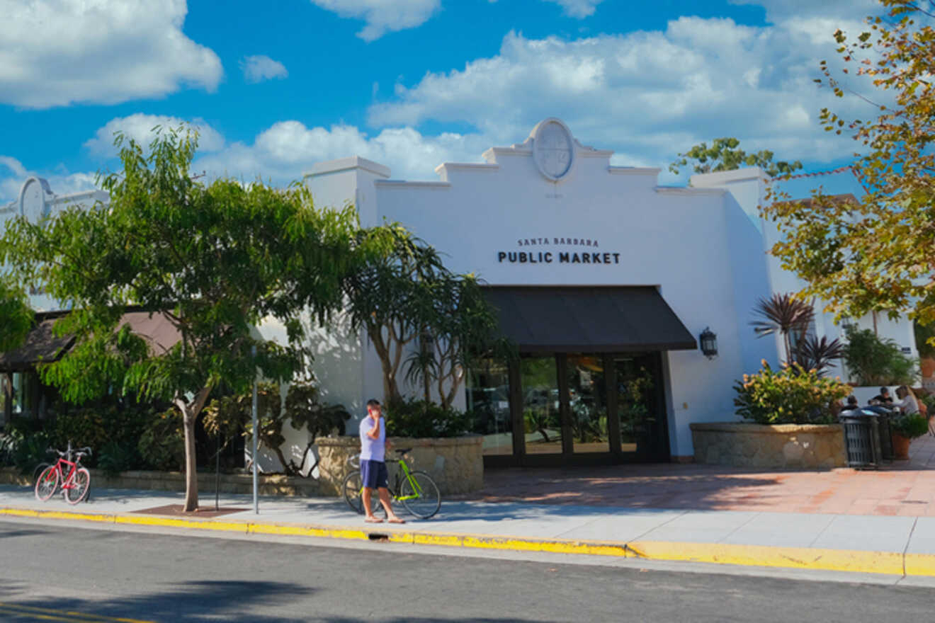 A man is walking down the street in front of a white building.