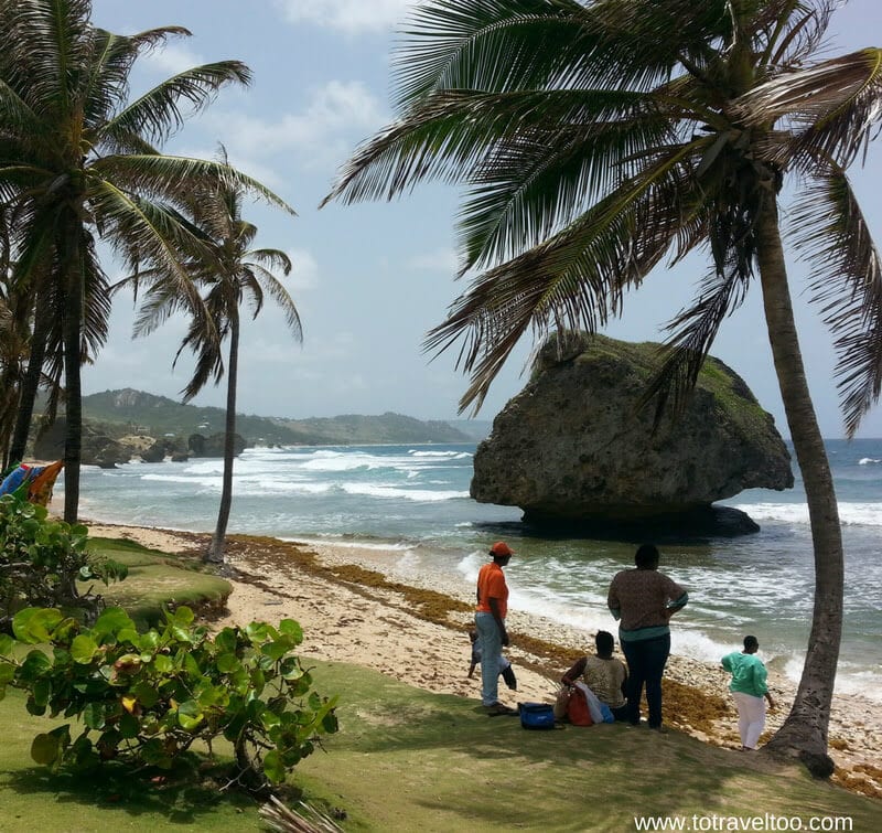 people on Bathsheba Beach with big rock offshore