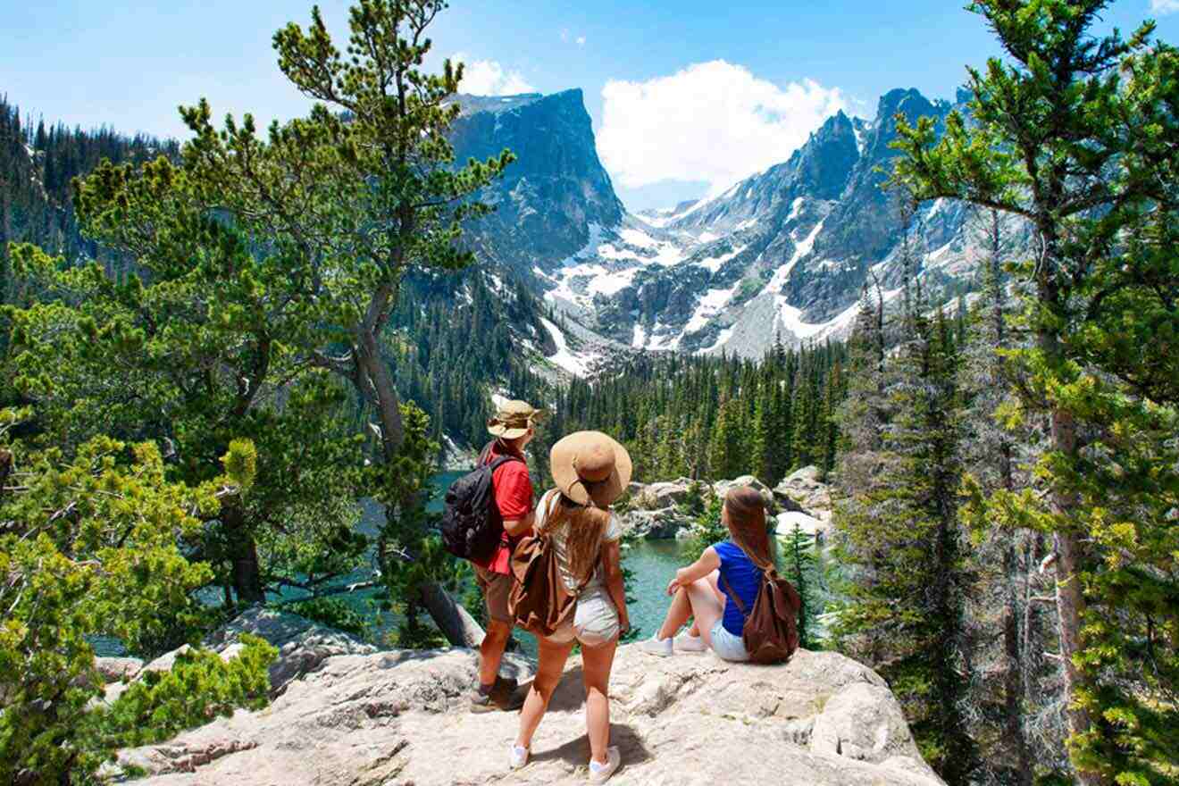 Three people standing on a rock overlooking a lake.