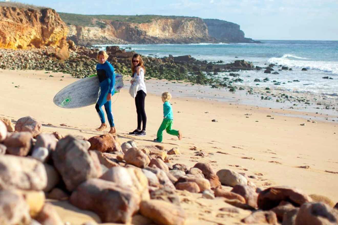 A group of people walking along the beach with surfboards.