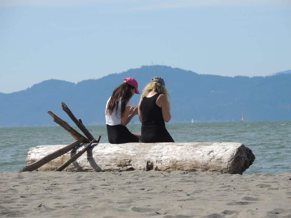 people sitting on log at Spanish Banks