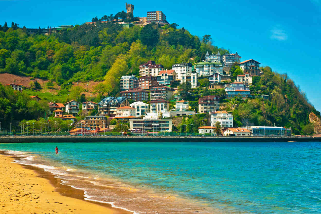 A beach with a small town on top of a hill.