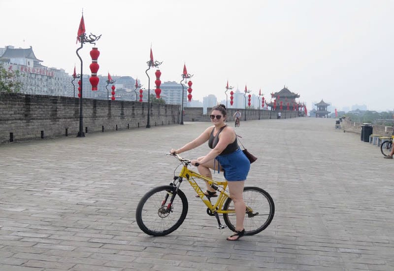 girl on bike in front of the city wall in Xian - 