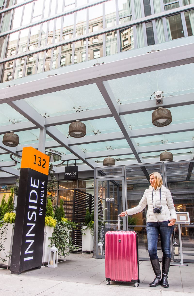 woman standing at hotel entrance with suitcase