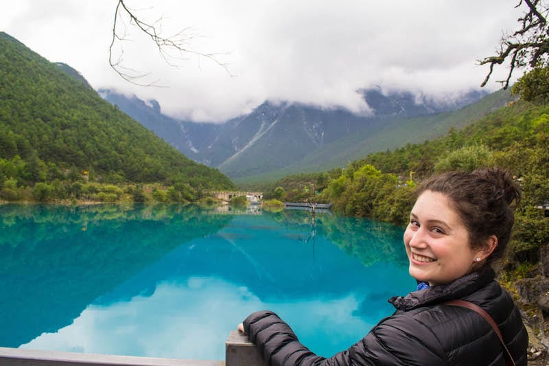 girl posing in front of blue lake Jiuzhaigou 