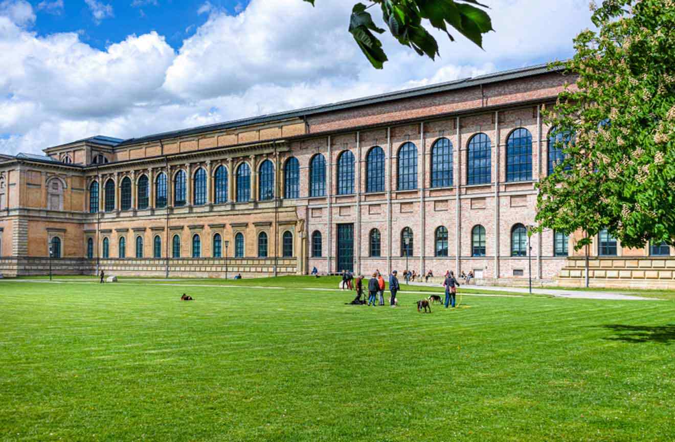 People are sitting on the grass in front of a large building.