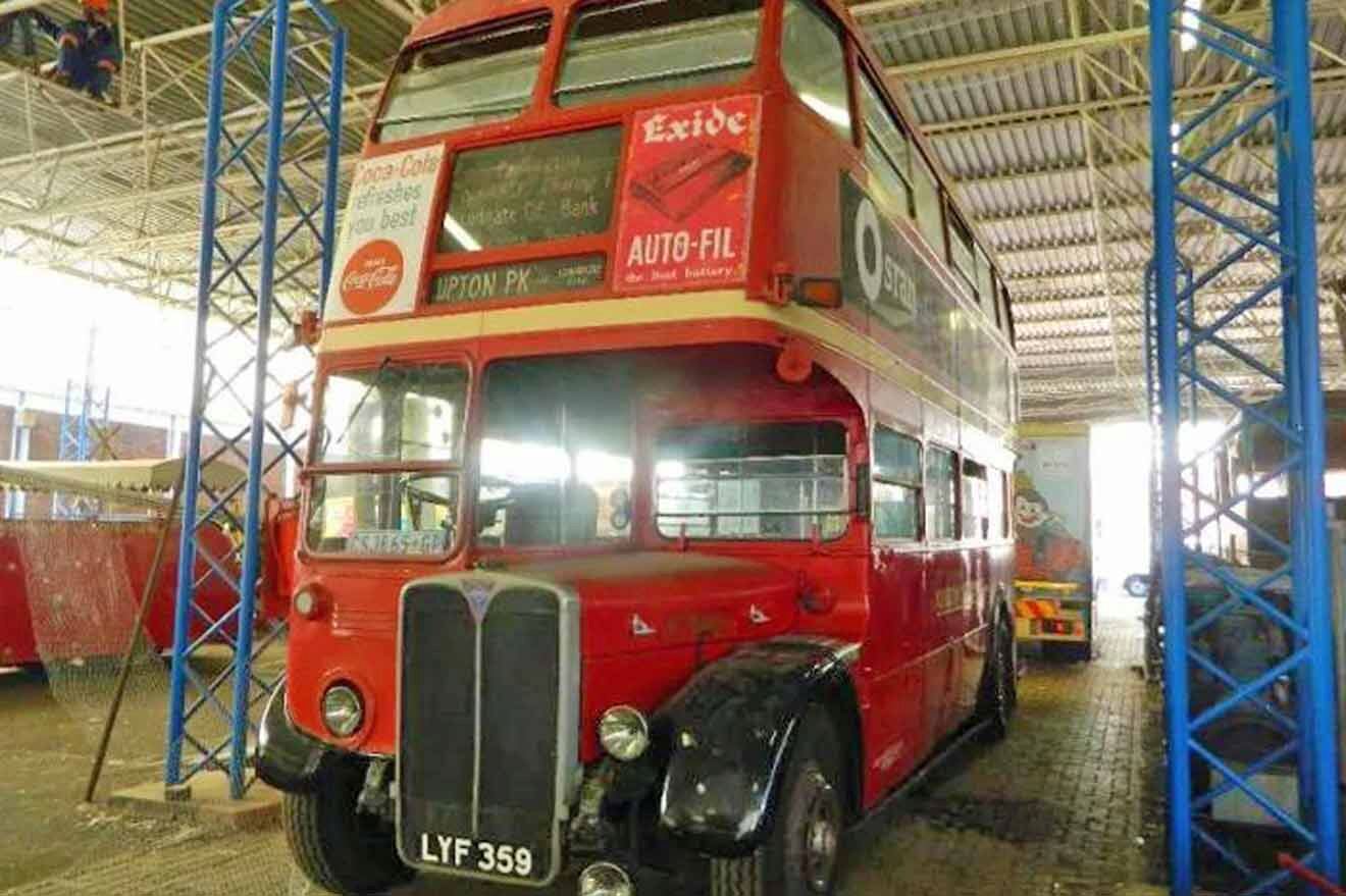 A red double decker bus is parked in a warehouse.