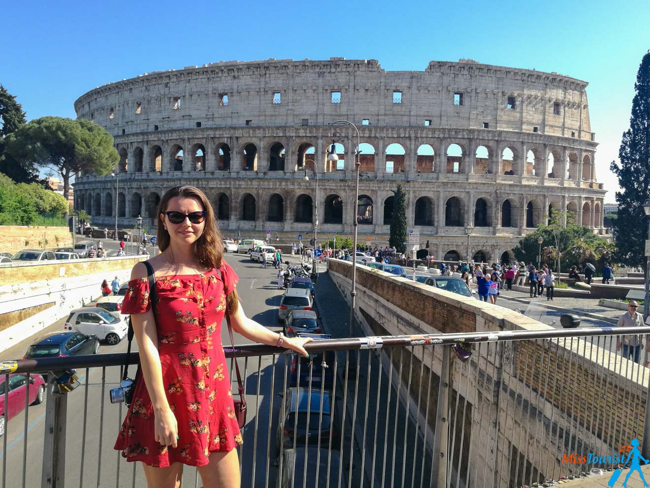 A woman in a red dress standing in front of the colossion.