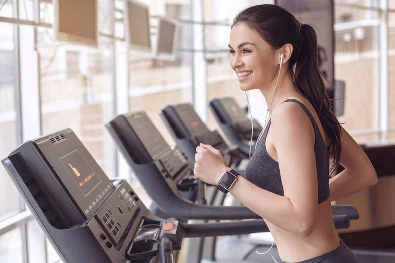 A woman is running on a tread machine in a gym.