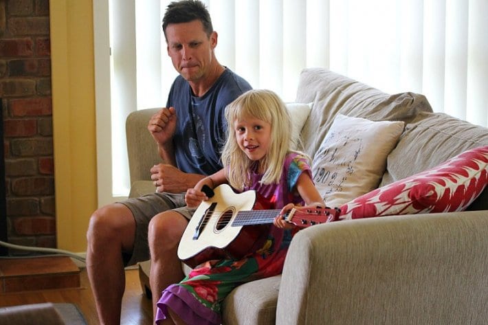 kalyra playing guitar on couch